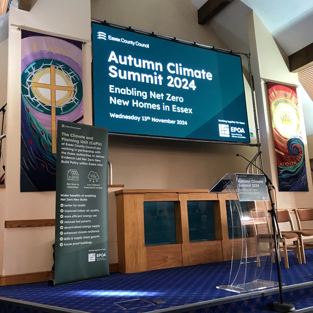 Empty lecturn in front of a screen reading 'Autumn Climate Summit 2024'